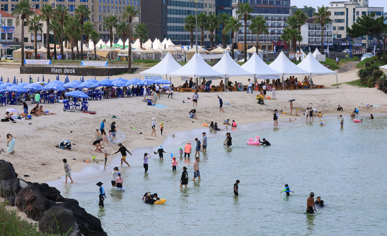 Visitors swim at Hamdeok Beach on Jeju Island, Saturday. (Yonhap)