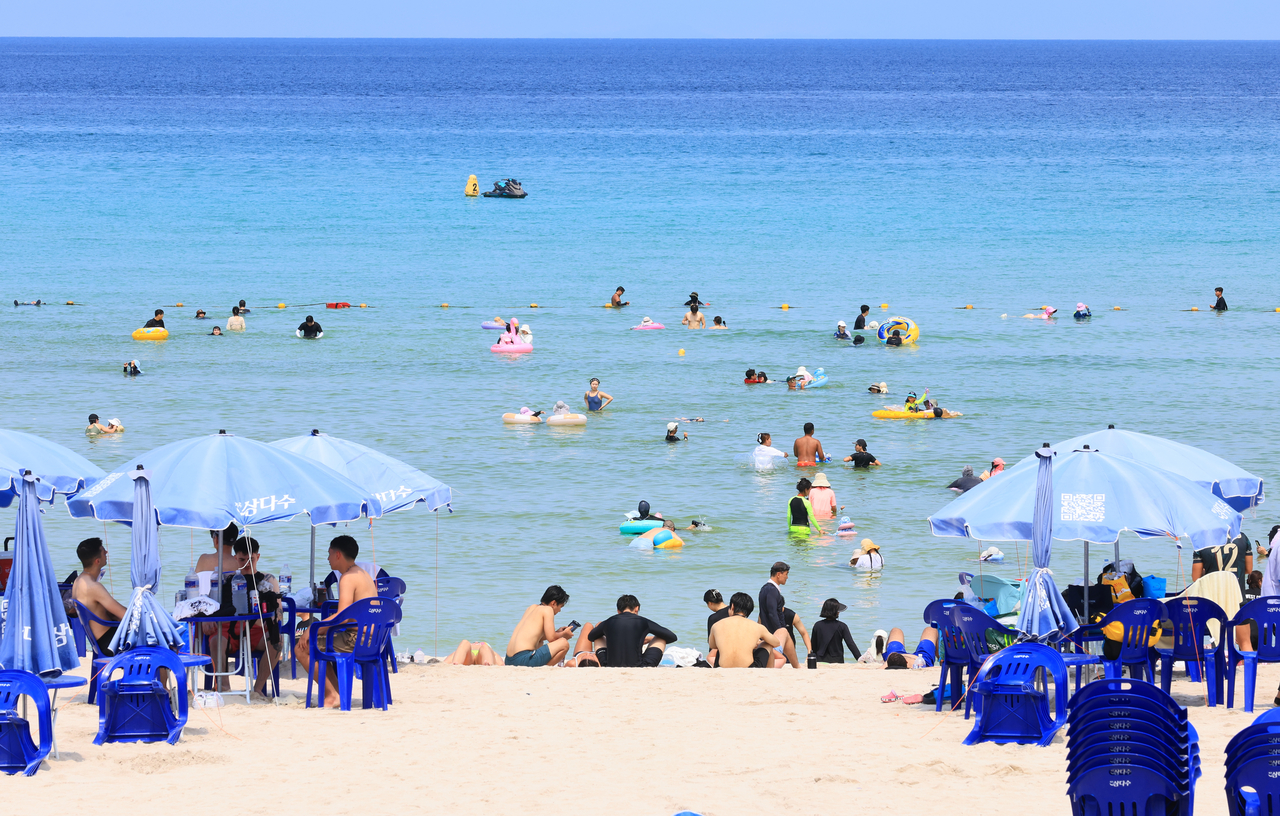Visitors swim at Hamdeok Beach on Jeju Island, Saturday. (Yonhap)