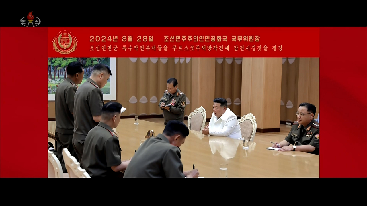 This image captured on Saturday from the music video of the song titled "Remember," aired by the Korean Central Television, showed North Korean leader Kim Jong-un (center, in white suit) presiding over a meeting with military officials. (Yonhap)