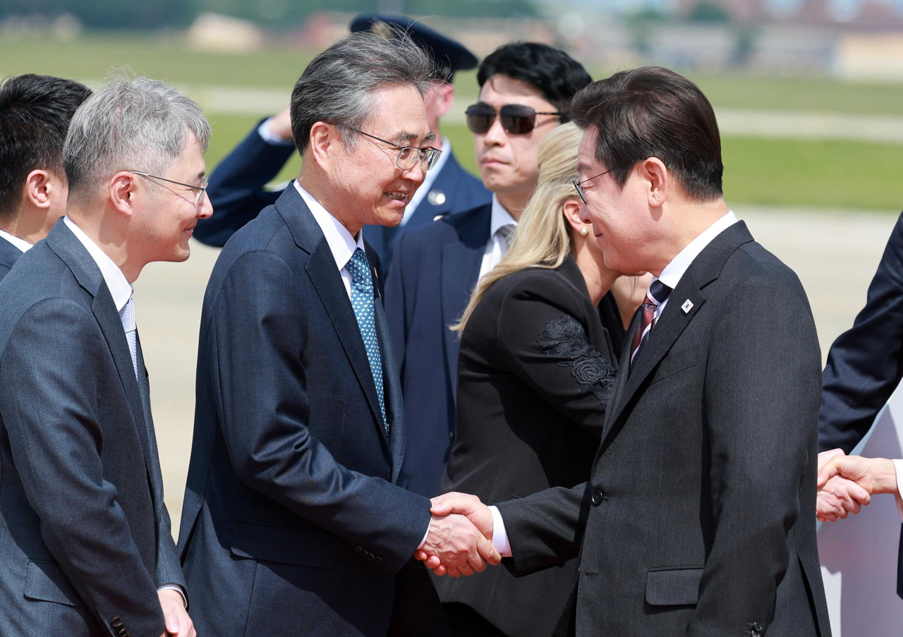 South Korean President Lee Jae Myung (right) shakes hands with South Korean Foreign Minister Cho Hyun as he arrives at Joint Base Andrews near Washington on Aug. 24, to attend his first summit with US President Donald Trump at the White House. (Yonhap)