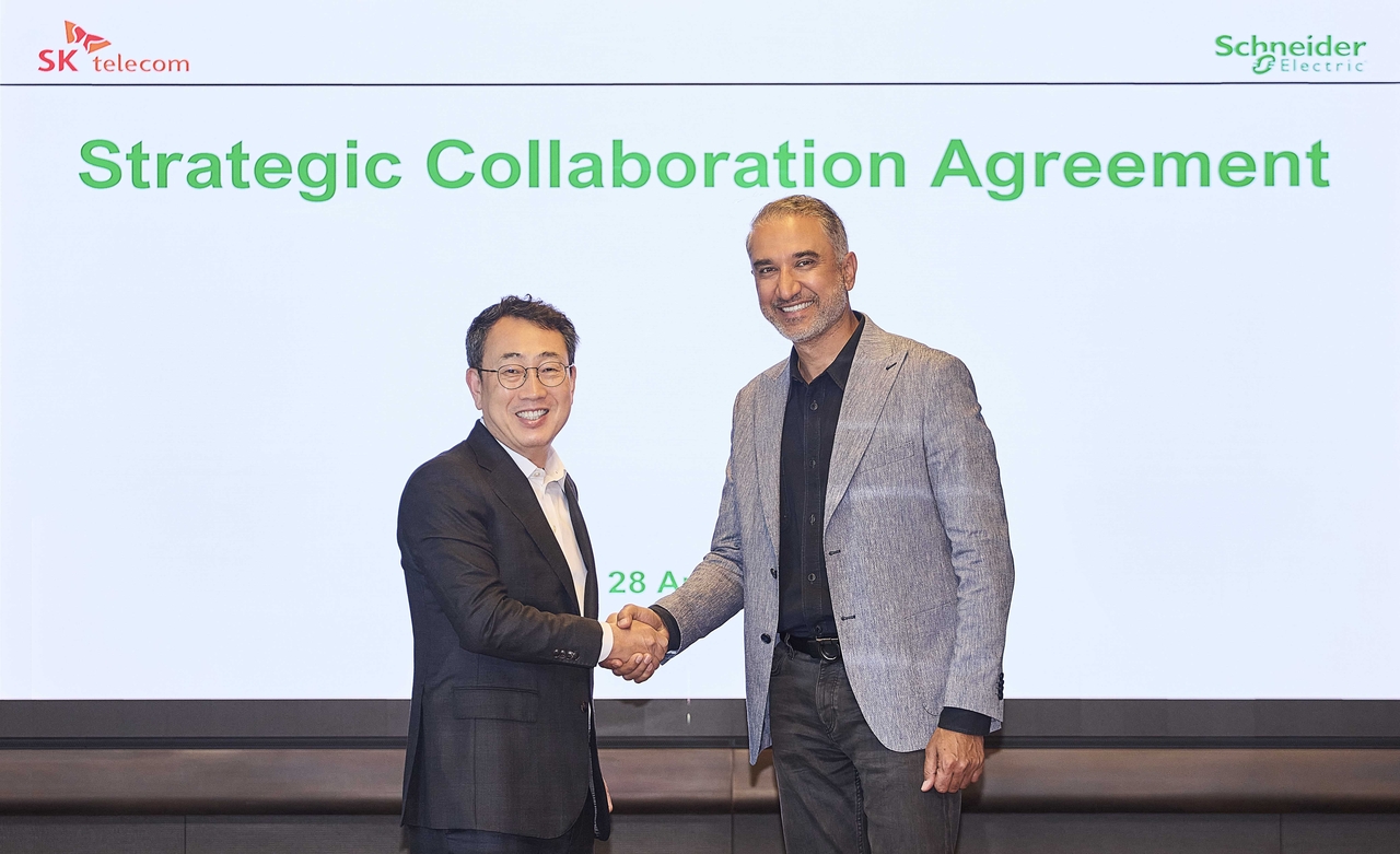 SK Telecom CEO Ryu Young-sang (left) and Schneider Electric Executive Vice President Pankaj Sharma shake hands after signing a strategic agreement in Seoul on Thursday. (SK Telecom)