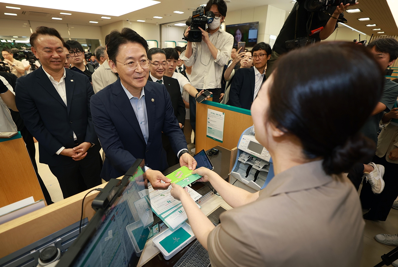 1일 서울 중구 하나은행 본점에서 열린 ‘토토사이트 순수익한도 1억원 시행 현장방문’ 행사에 권대영(가운데) 금융위 부위원장과 유재훈(뒷줄 왼쪽) 예금보험공사 사장, 이호성(뒷줄 오른쪽) 하나은행장 등이 참석했다. 권 부위원장이 이날 영업점에서 개설한 통장을 받고 있다.  [금융위원회 제공]