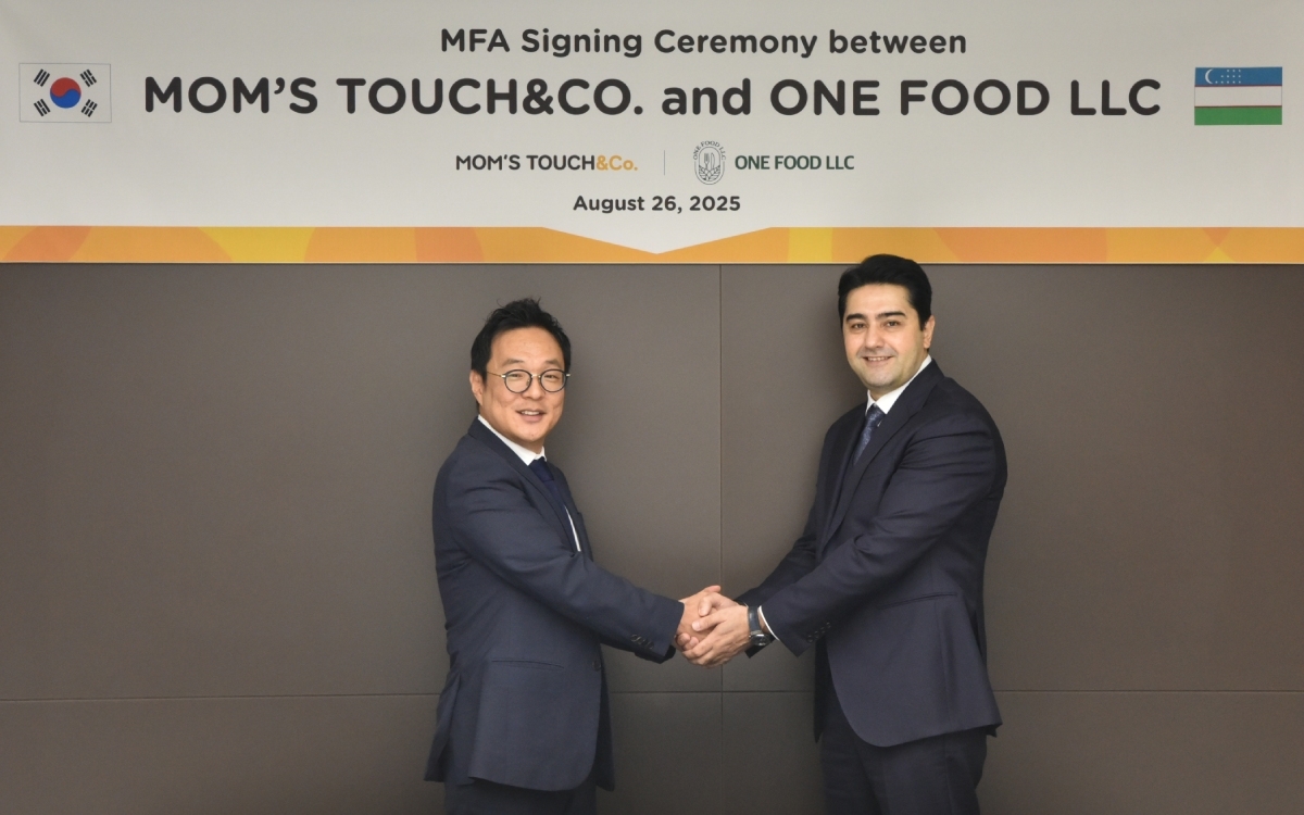 Mom's Touch CEO Kim Dong-jeon (left) and One Food CEO Khodjaev Zafar Zalulovich shake hands after signing a master franchise agreement in Seoul on Aug. 26. (Mom's Touch)