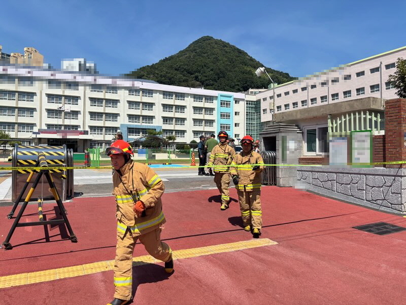 Firefighters dispatched to a Busan high school on Friday respond to a bomb threat made via fax earlier in the day. (Yonhap)