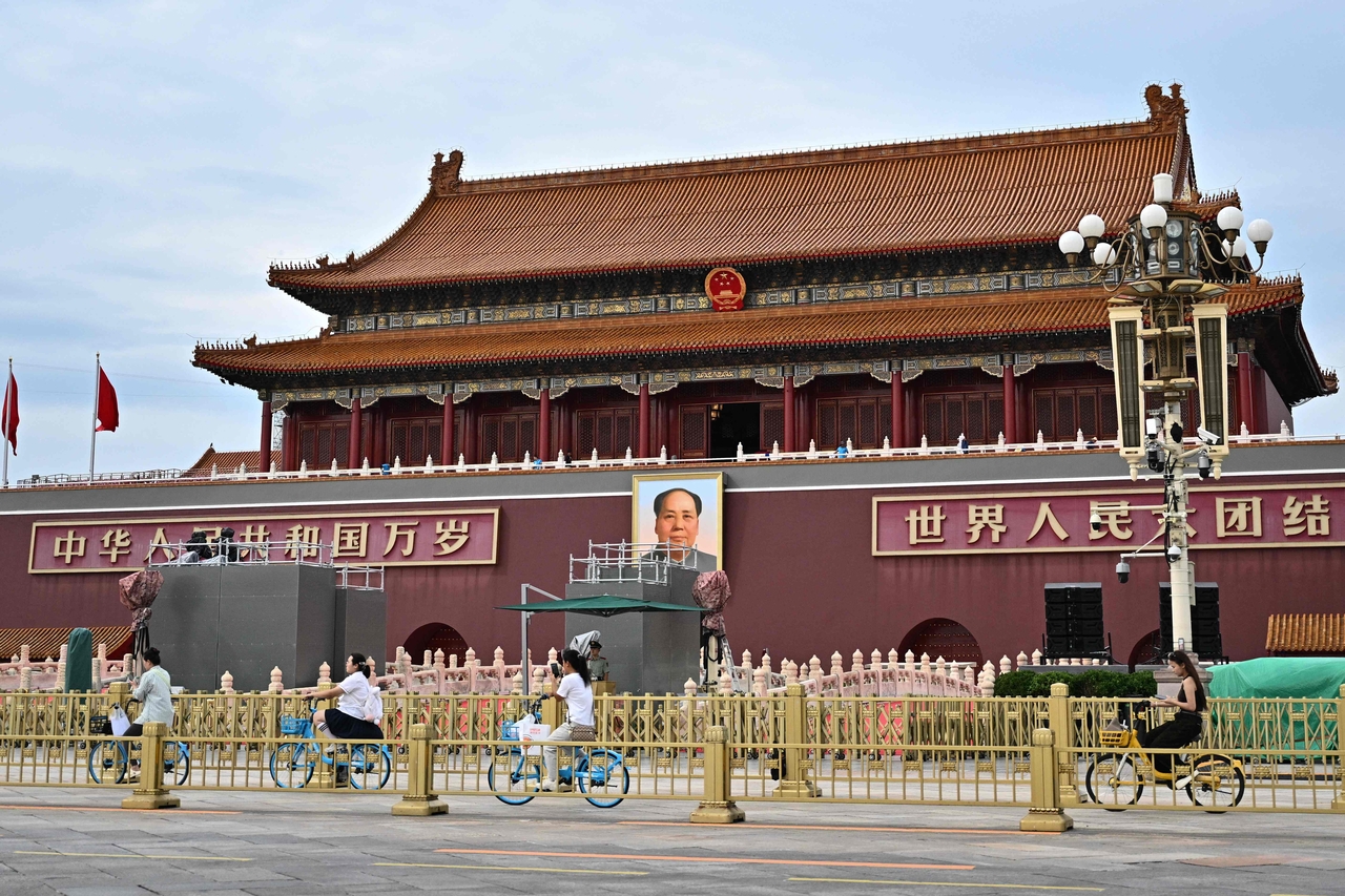 People ride past a portrait of the late communist leader Mao Zedong on Tiananmen Square, where the next military parade will take place on September 3 to mark the 80th anniversary of victory over Japan and the end of World War II, in Beijing on Aug 28. (AFP)