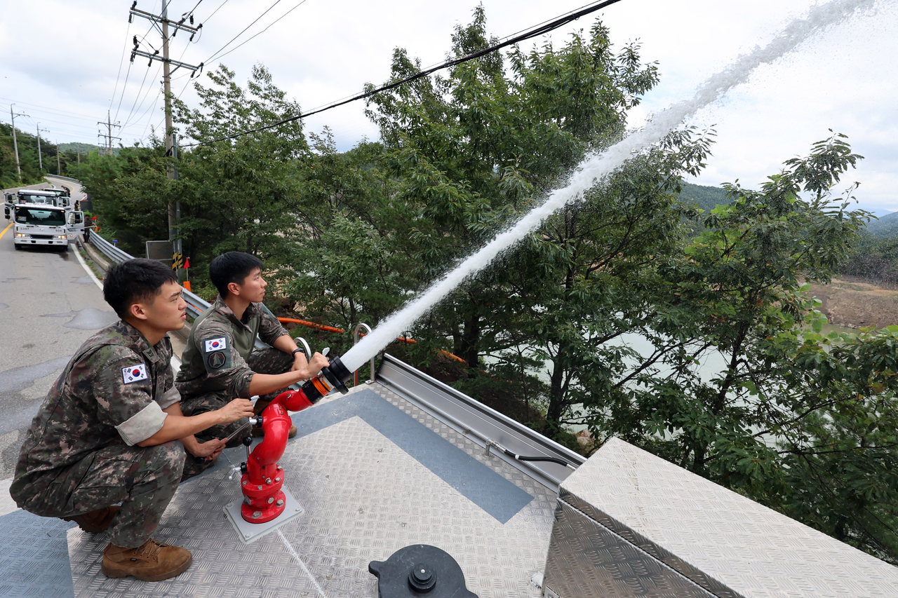 Military personnel in Gangneung, Gangwon Province, pour water brought in by military water tanks into the Obong Reservoir, as the city struggles with one of its worst droughts in history, Tuesday. (Yonhap)