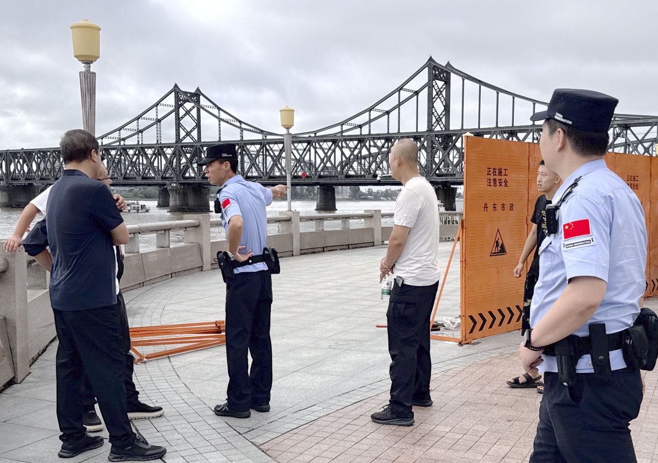 Chinese officials install fences near the Yalu River Bridge on Monday, ahead of the expected crossing of a private train carrying North Korean leader Kim Jong-un. (Yonhap)