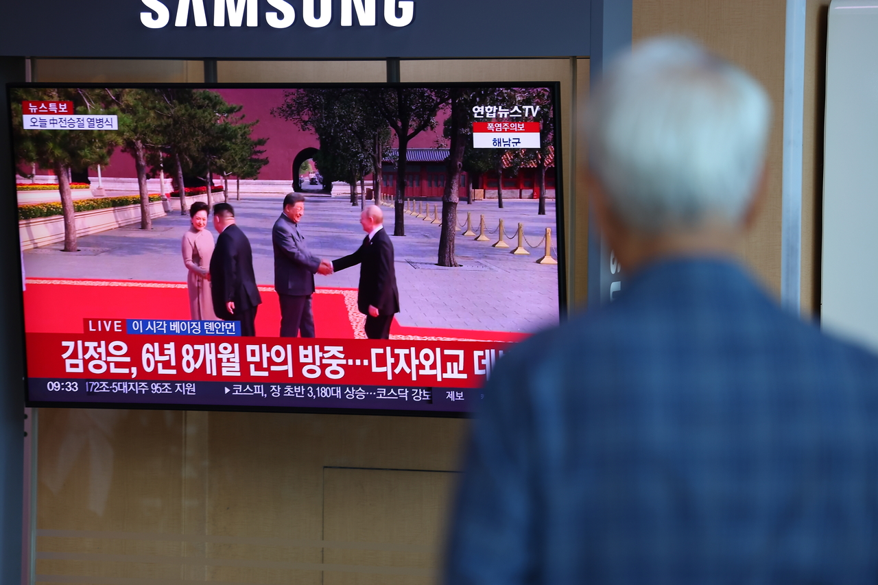 A passenger watches news coverage of a large military parade in Beijing marking the 80th anniversary of Victory Day, at Seoul Station’s waiting area on Wednesday. (Yonhap)