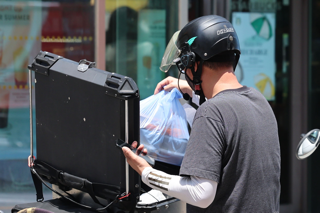 A delivery worker carries food orders in Seoul in June. (Newsis)