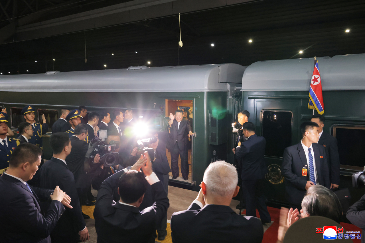 North Korean leader Kim Jong-un waves as he boards his private train at Beijing Station on Saturday , to head home following his summit talks with Chinese President Xi Jinping, in this photo released by the North's official Korean Central News Agency the next day. (Yonhap)