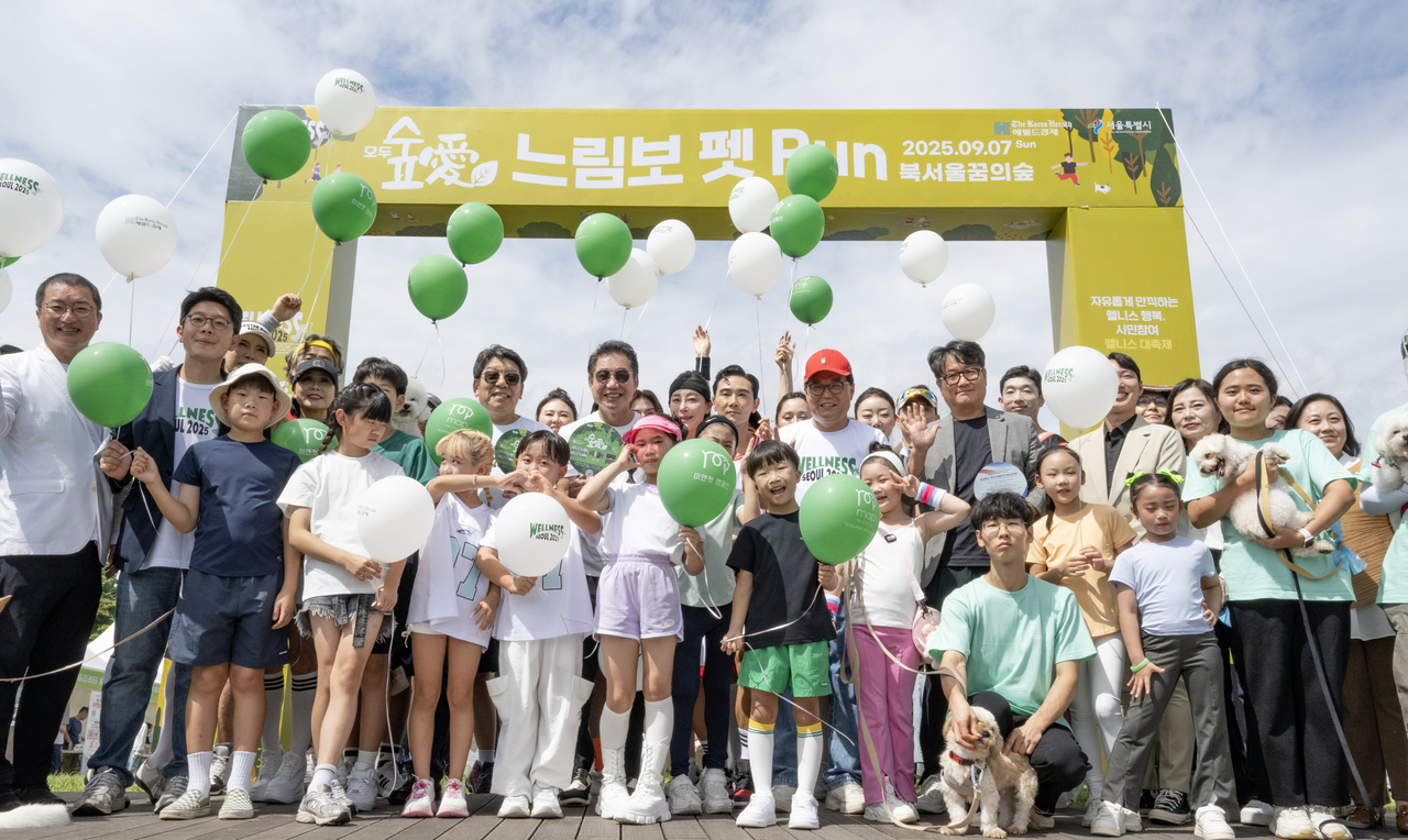 Participants of the Slow Marathon with Pets, including Herald Media Group CEO Choi Jin-young and Seoul Deputy Mayor for Political Affairs Kim Byung-min, pose with their companions for a photo during the Wellness Seoul 2025 festival at Dream Forest on Sunday. (Im Se-jun/ The Korea Herald)