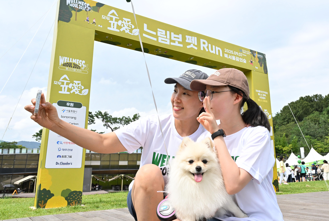 Participants take a selfie with their dog ahead of the Slow Pet Marathon during the Wellness Seoul 2025 festival at Dream Forest on Sunday. (Im Se-jun/The Korea Herald)