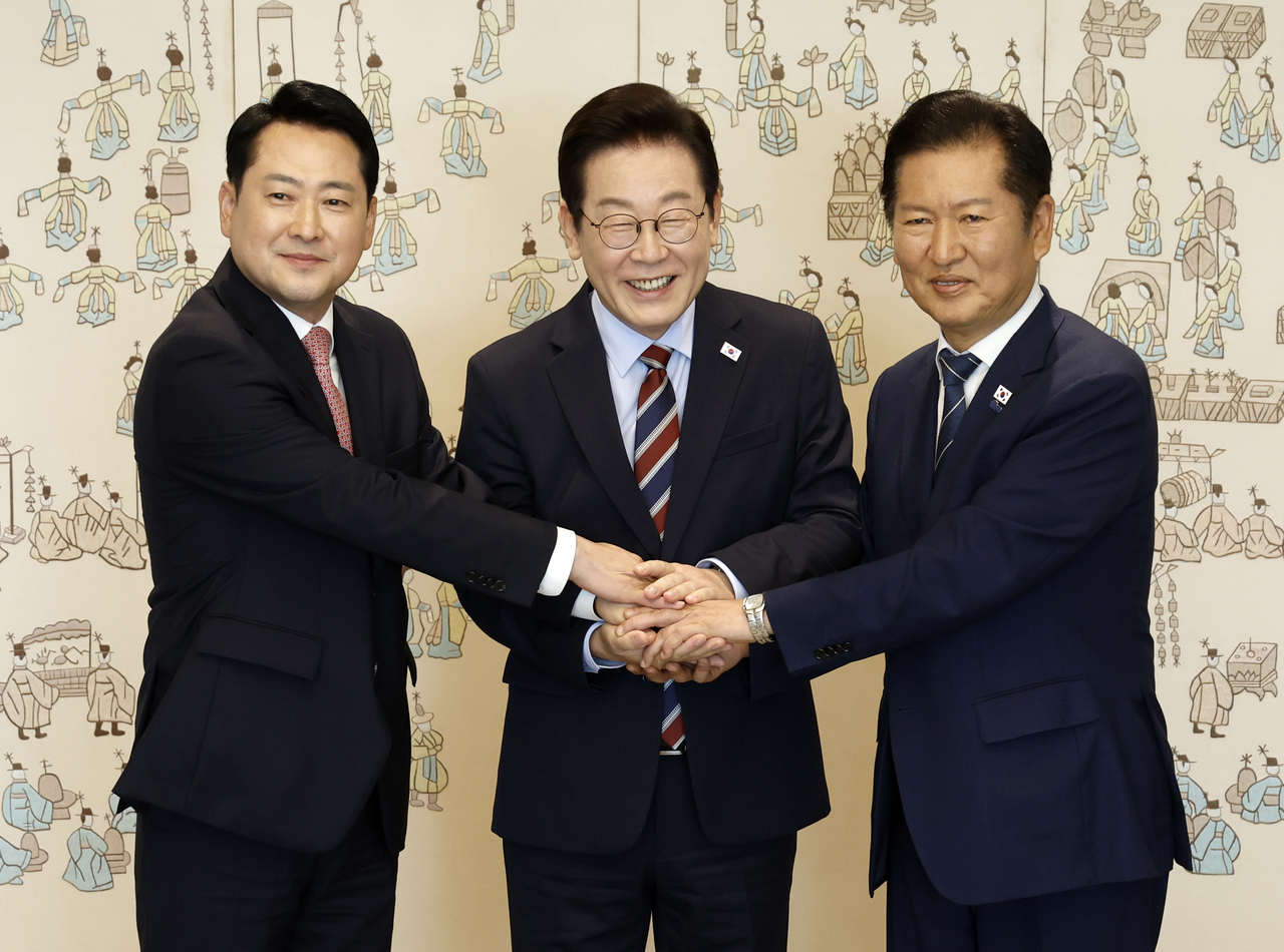 President Lee Jae-myung (center) shakes hands with the leaders of the two rival parties at the presidential office in Seoul on Monday. (Yonhap)