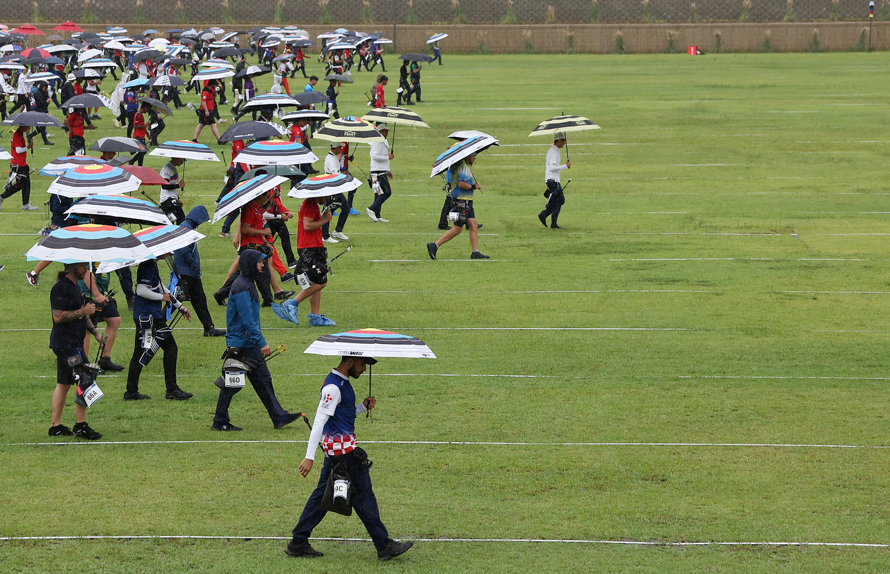 Holding umbrellas, players walk to check their scores at the Gwangju International Archery Center in Nam-gu, Gwangju, during the preliminary round of the recurve individual event at the 2025 World Archery Championships on Tuesday. (Yonhap)
