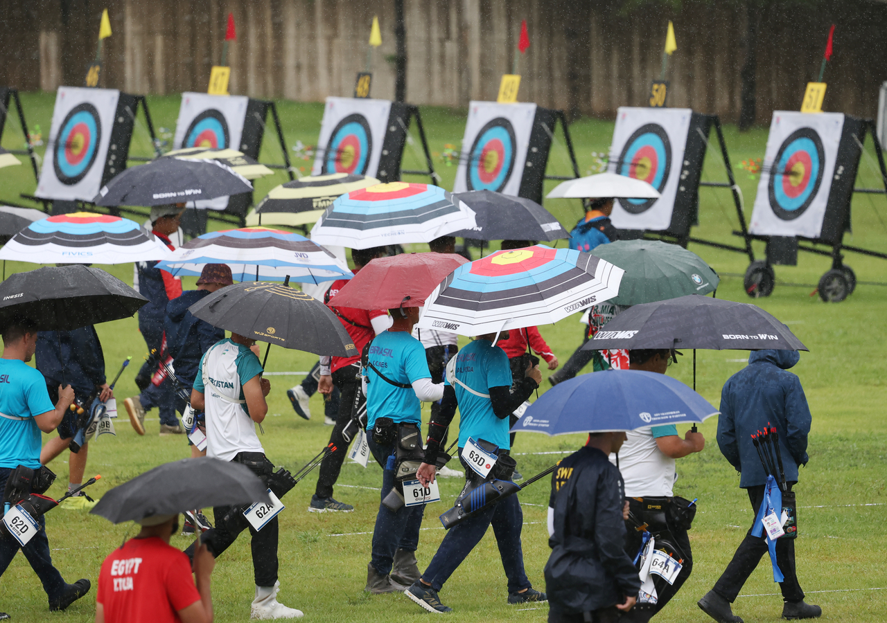 Holding umbrellas, players walk to check their scores at the Gwangju International Archery Center in Nam-gu, Gwangju, during the preliminary round of the recurve individual event at the 2025 World Archery Championships on Tuesday. (Yonhap)