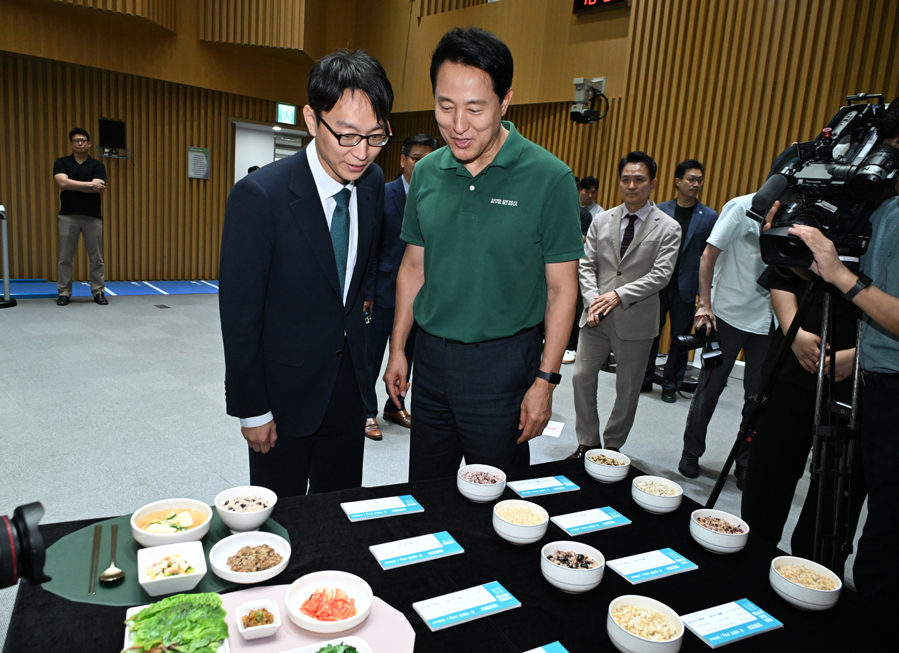 Seoul Mayor Oh Se-hoon (right) looks at healthy food options such as whole grain and mixed grain rice as well as side dishes featuring vegetables and protein during a press briefing on the city government’s health initiative targeting its citizens at Seoul City Hall on Wednesday. (Seoul Metropolitan Government)