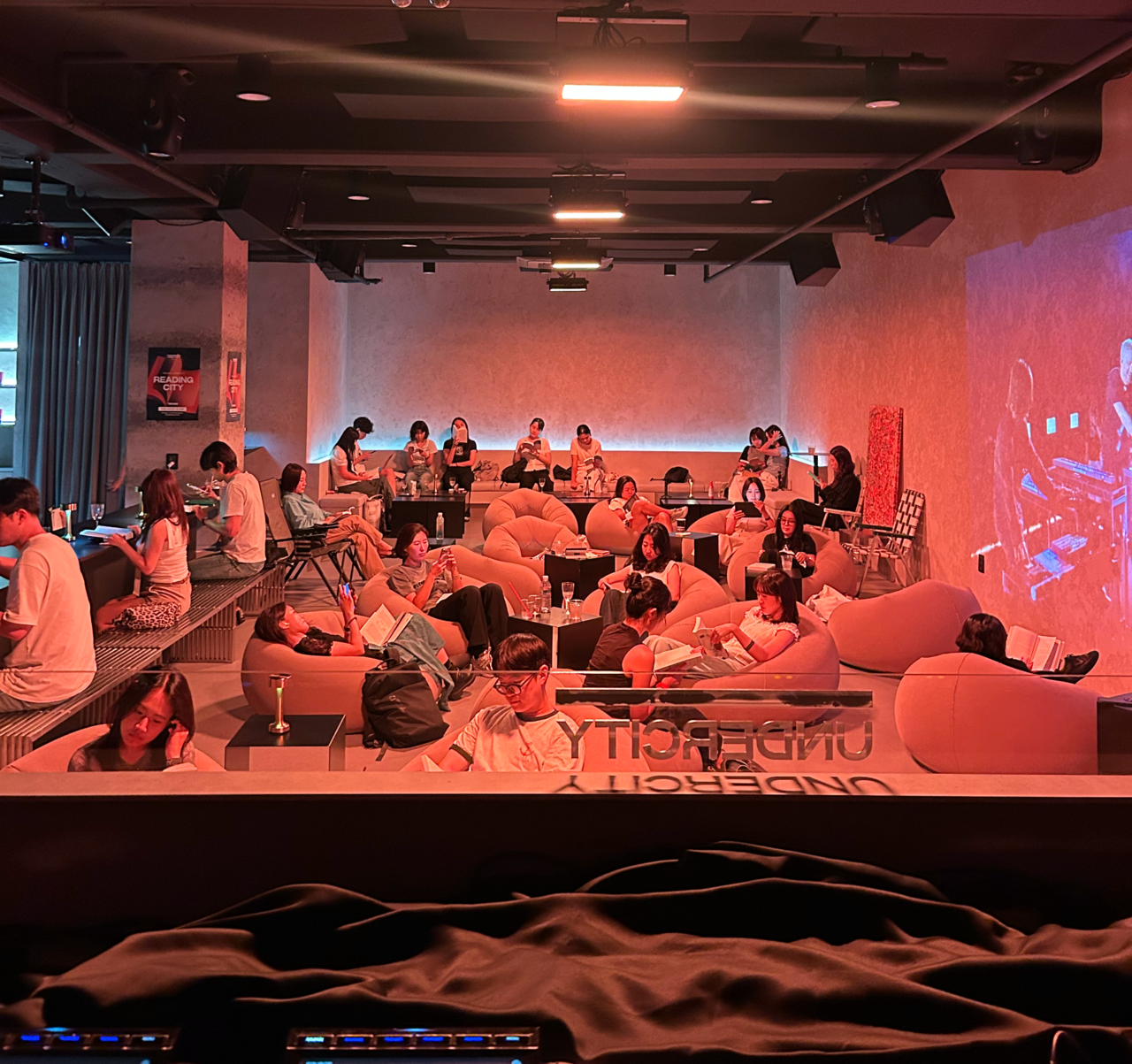 Participants read books while listening to low-tempo electronic music during Reading City, co-organized by electronic music event planner Undercity and book club Trevari, in the basement of a building in Seongsu-dong, Seoul, on Aug. 26. (Undercity)