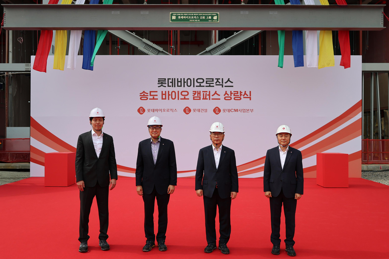 Top executives of Lotte Biologics, including Chief Strategy Officer Shin Yoo-yeol (left) and CEO James Park (second from left), pose for a photo during the company's topping out ceremony for its first plant at the Songdo Bio Campus in Incheon on Tuesday. (Lotte Biologics)