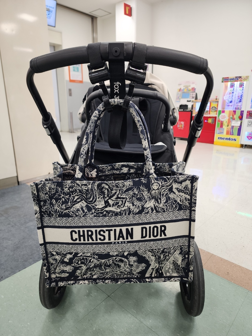 A Dior Book Tote Large hanging from a stroller (Courtesy of Bae)