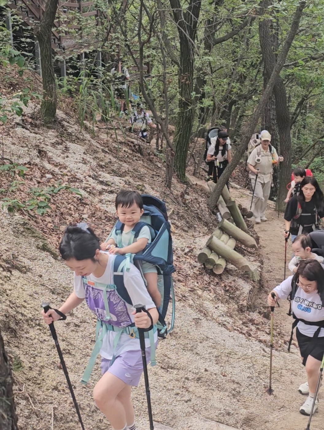 Members of the Baby Hiking Club climb up the trail with their babies on their backs.  (Choi Jae-hee/The Korea Herald)