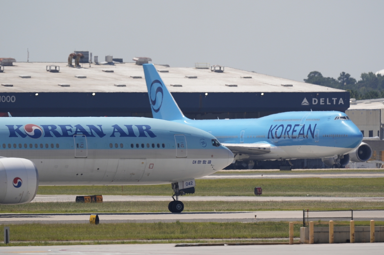 A Korean Air passenger plane, left, takes off as a charter plane, right, sits parked at Hartsfield-Jackson International Airport in Atlanta on Wednesday. (AP-Yonhap)