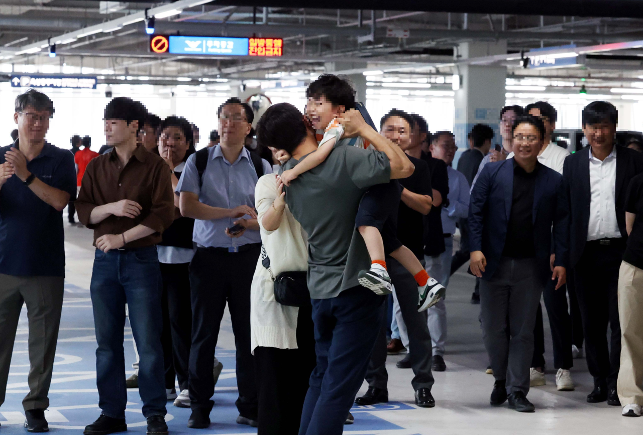 Korean workers who were detained in a US immigration raid in Georgia reunite with their families at Incheon Airport, where they landed Friday on a chartered flight. (Yonhap)