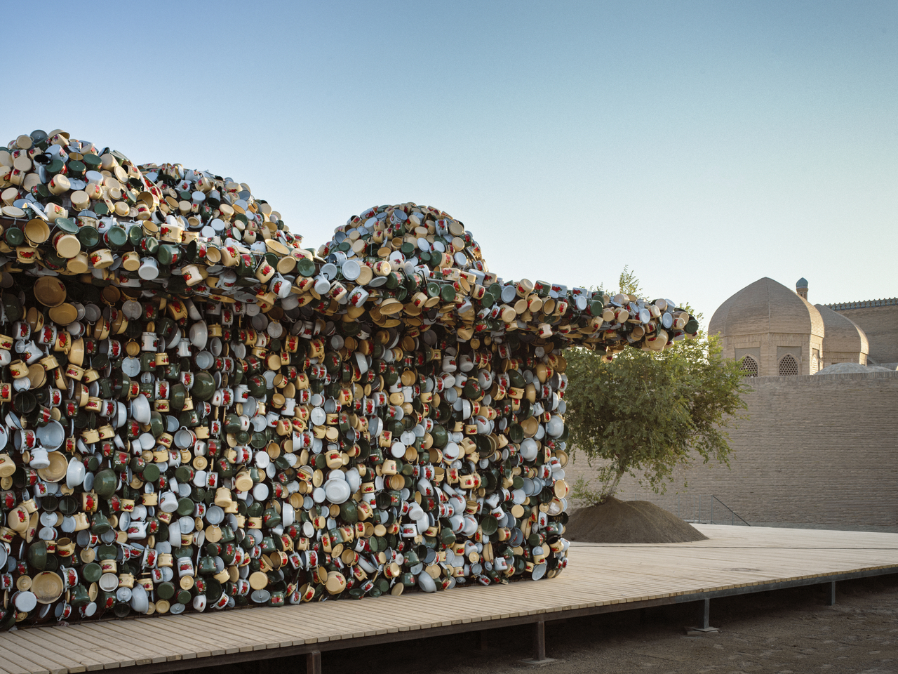 "Salt Carried by the Wind" (2024–2025) by Subodh Gupta of India with tableware by Baxtiyor Nazirov of Uzbekistan stands next to Magoki Attori, the oldest standing mosque in Central Asia, in Bukhara, Uzbekistan. (Uzbekistan Art and Culture Development Foundation.)