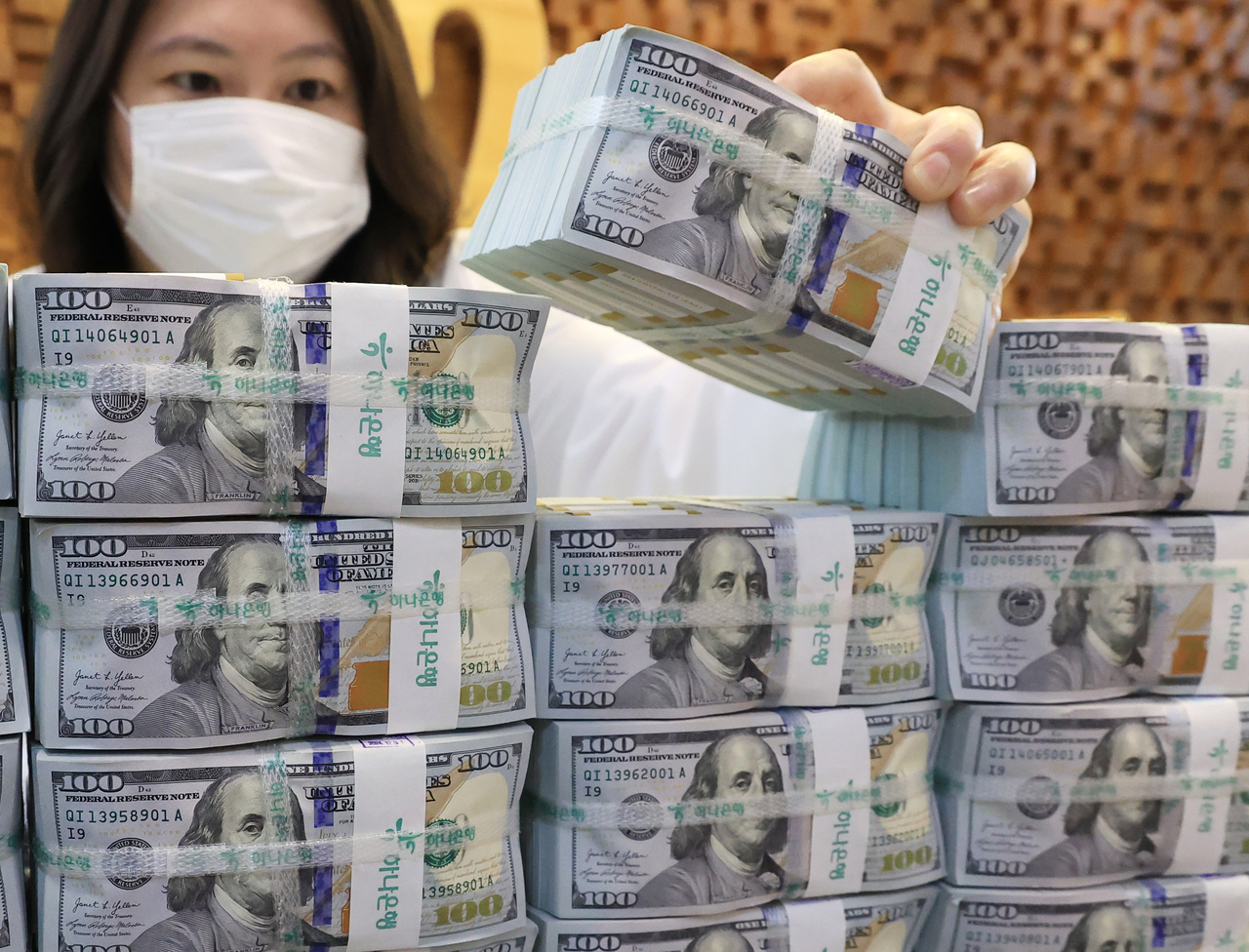 A banker at Hana Bank’s headquarters in central Seoul holds a stack of dollar bills on Sept. 3. (Yonhap)