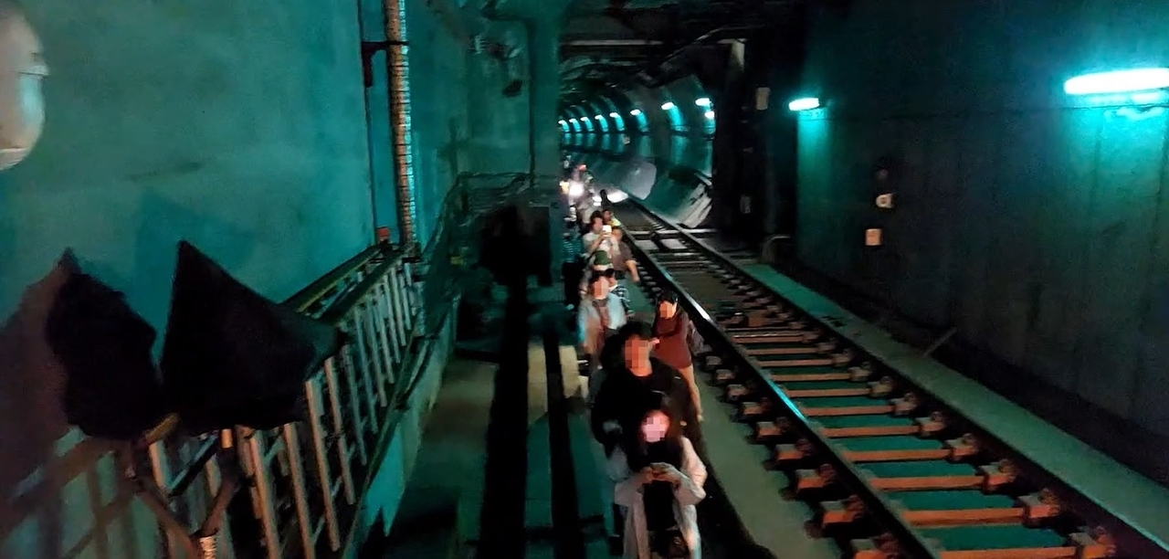 Passengers walk along the tracks to evacuate through a tunnel after a fire broke out on Seoul Subway Line No. 5 between Yeouinaru and Mapo stations on May 31, using phone flashlights to guide one another in the dark. (Yeongdeungpo Fire Station)