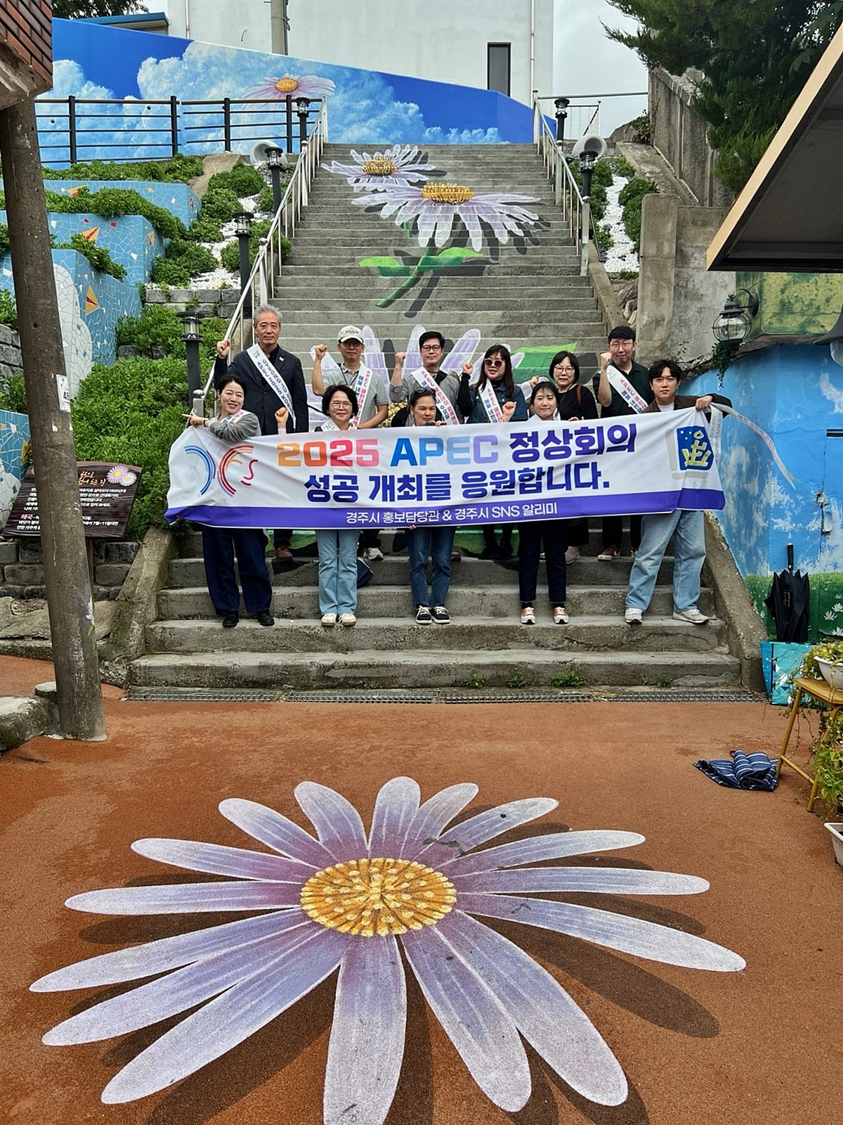 지난 11일 경주시 감포 해국길에서 열린 ‘SNS 알리미 팸투어 및 APEC 클린데이’ 참가자들이 2025 APEC 정상회의 성공 개최를 응원하며 기념촬영을 하고 있다.[경주시 제공]