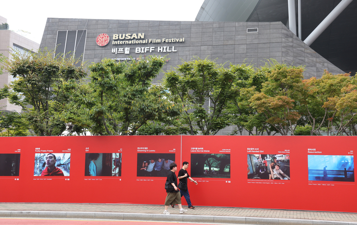 Pedestrians walk past a wall of posters for the 30th Busan International Film Festival at the Busan Cinema Center, the festival’s main venue in Haeundae-gu, Busan, Monday. (Yonhap)
