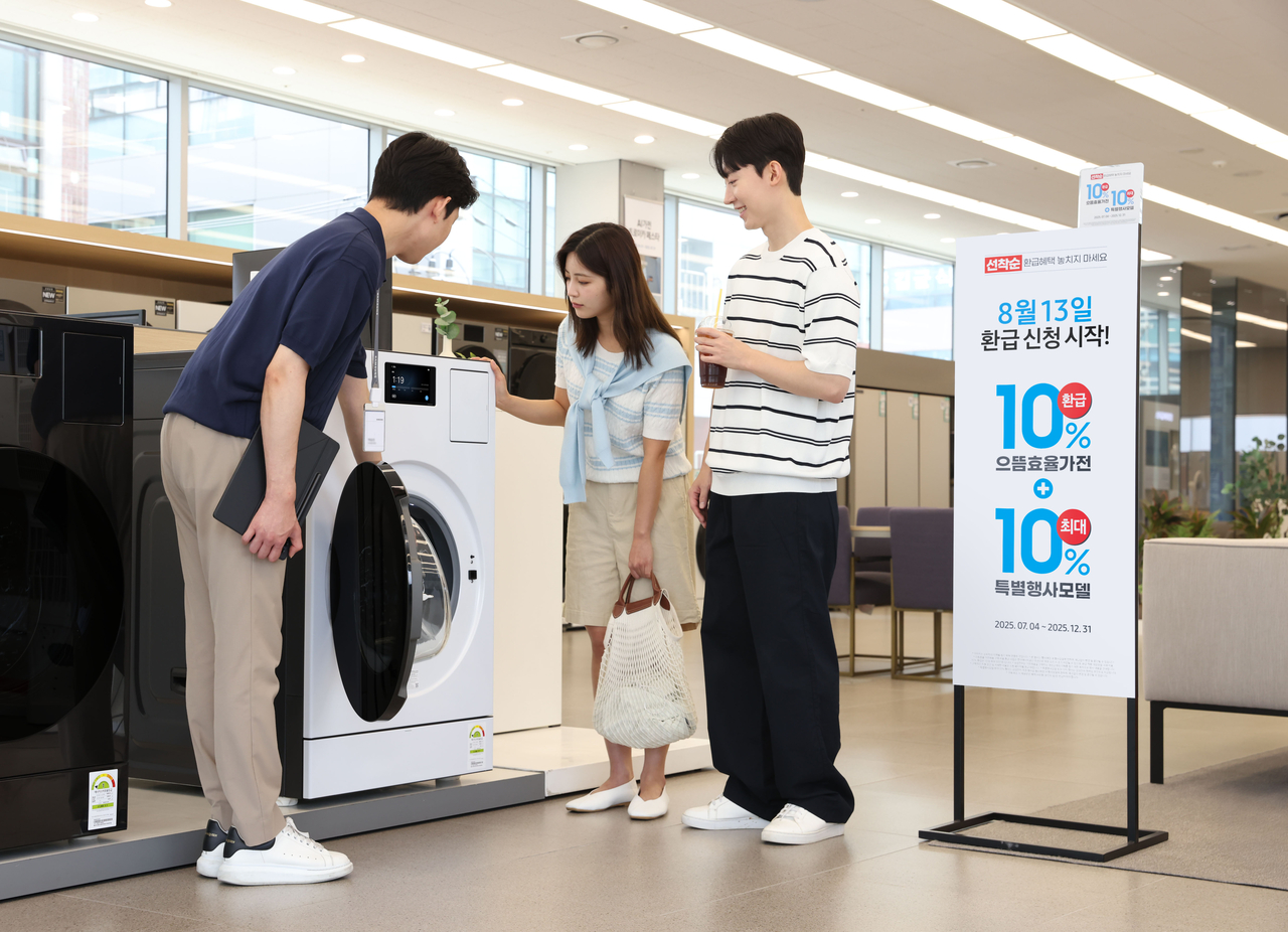 삼성전자 모델이 에너지 소비효율 1등급의 ‘세탁건조기’와 ‘에어컨’ 제품의 설명을 듣고 있다. 2025.8.14 [삼성전자 제공]