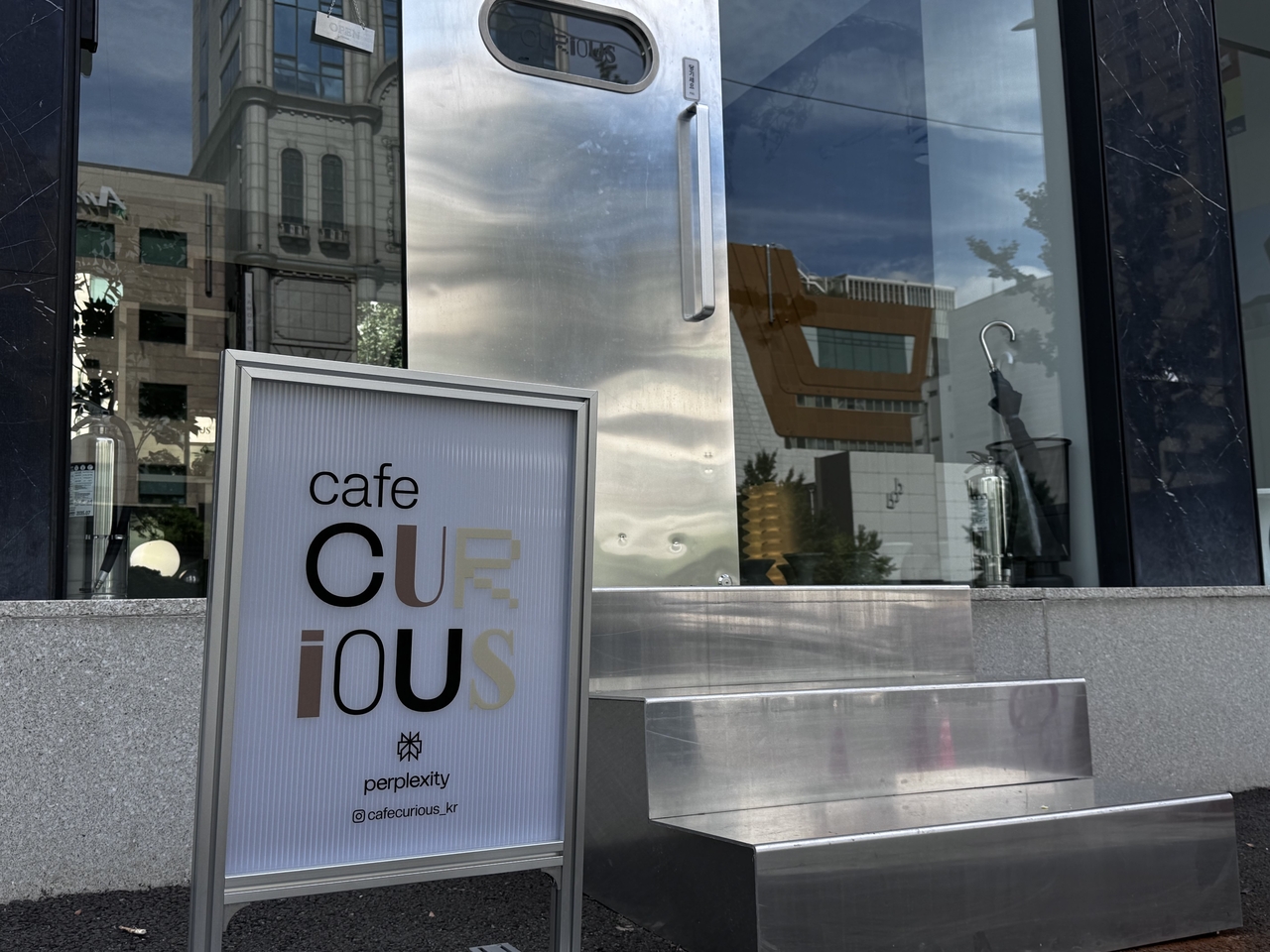 A small sidewalk sign is one of the few visible clues that Cafe Curious is operated by AI search company Perplexity. (Moon Joon-hyun/The Korea Herald)
