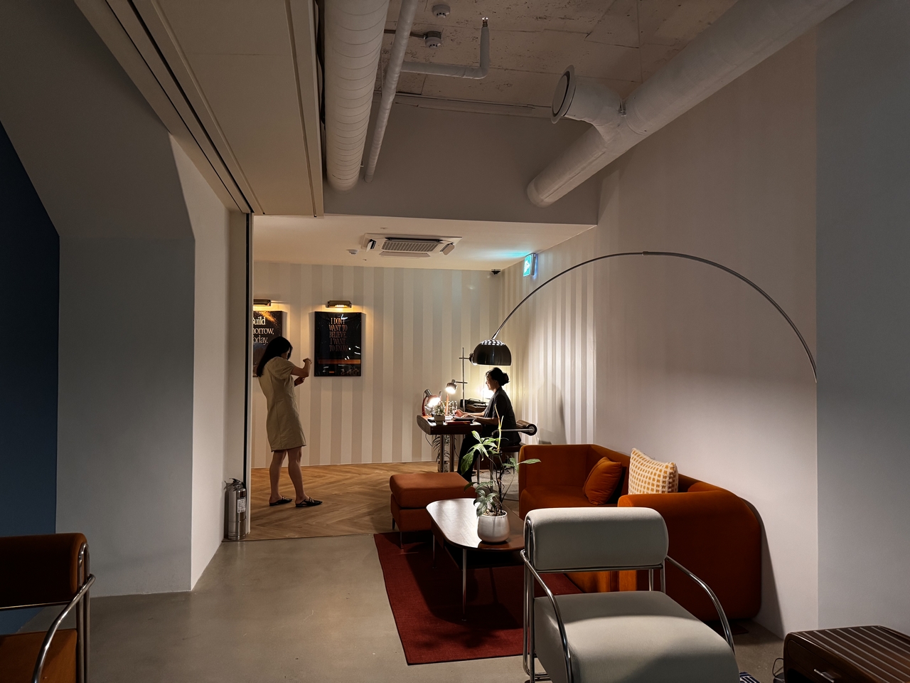 The basement lounge blends deep orange armchairs, striped walls and low lighting to create a quiet, semi-private space beside the AI demo area. (Moon Joon-hyun/The Korea Herald)