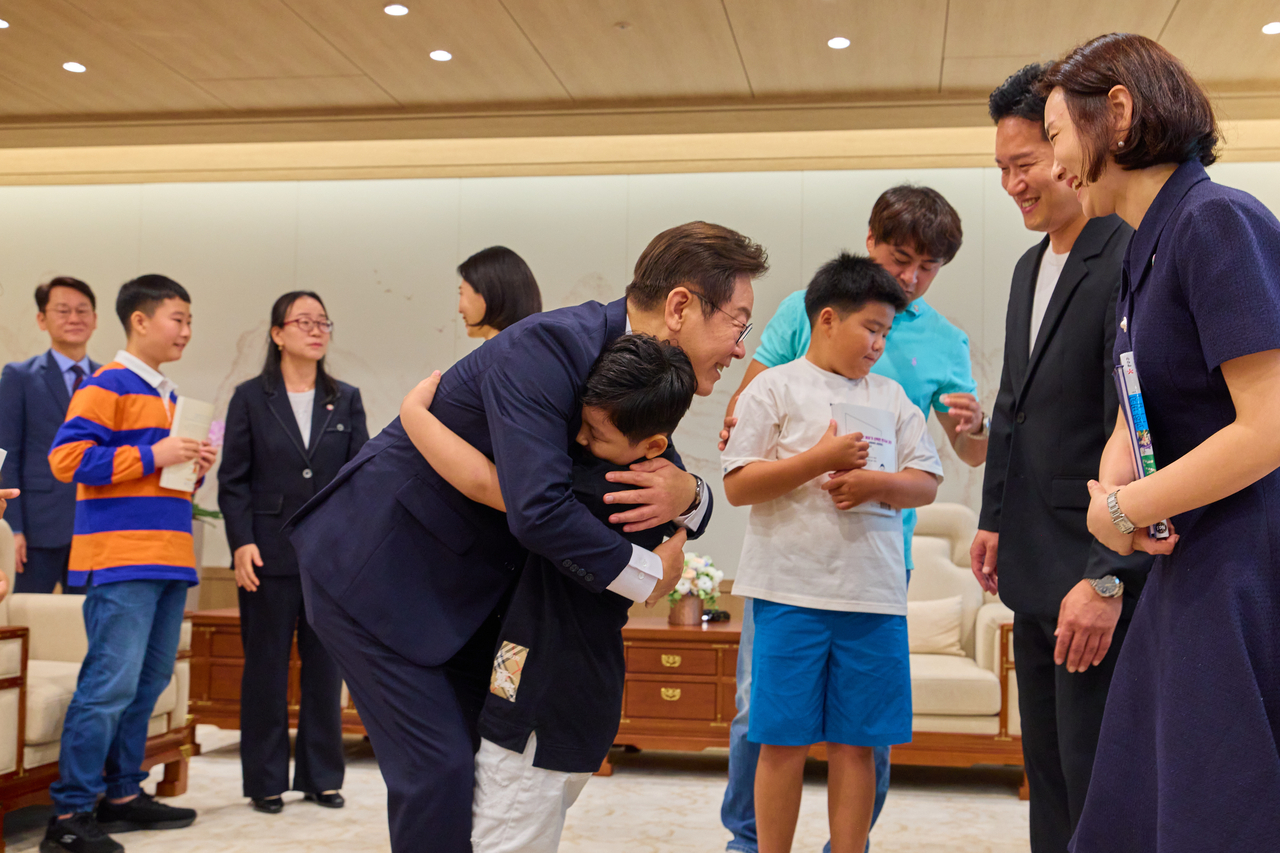 President Lee Jae Myung hugs a boy invited to an event held at the presidential office in Yongsan, central Seoul, Sept. 4. (Yonhap)