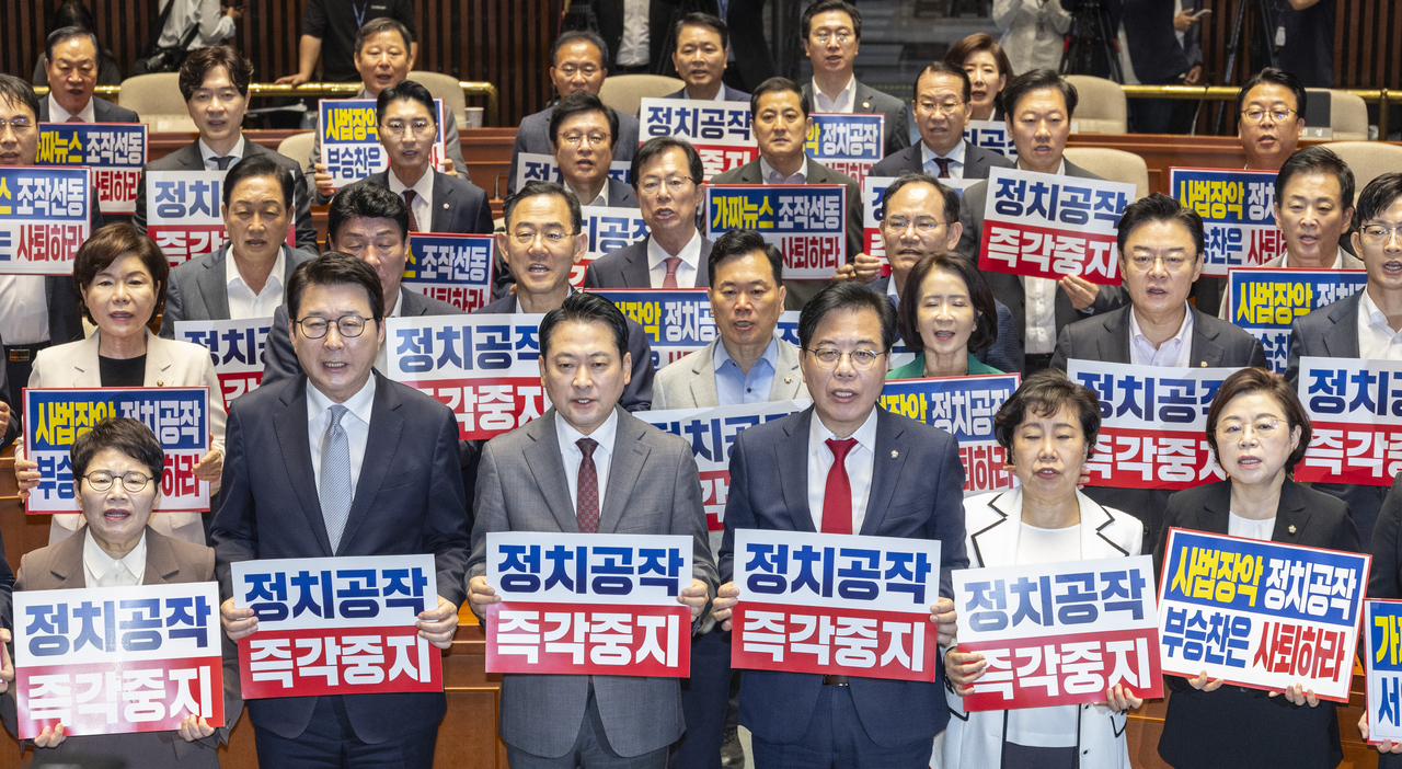 People Power Party Chair Rep. Jang Dong-hyeok (third from left in the front row) and floor leader Rep. Song Eon-seog (to Jang’s left), along with other party lawmakers, hold placards reading "Stop political manipulation" during a general assembly of the party at the National Assembly in Seoul on Friday. (Yonhap)