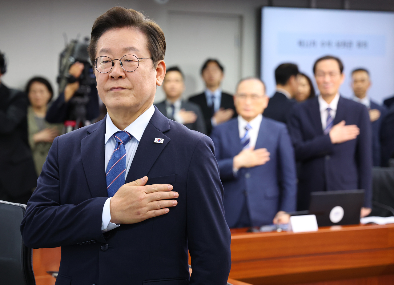 President Lee Jae Myung salutes the national flag during his meeting with his secretaries at his office in Seoul on Thursday. (Yonhap)