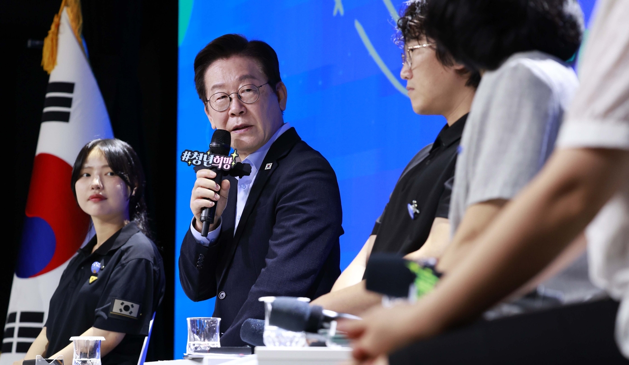 President Lee Jae Myung (2nd from left) talks with a participant at an event with people in their 20s and 30s held at a theater in Seoul on Sept. 19, 2025. (Pool photo) (Yonhap)
