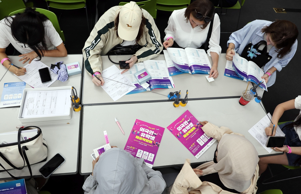International students prepare resumes and review company brochures during the 2025 Job Fair for International Students held on Aug. 19 at BEXCO in Busan. (Newsis)