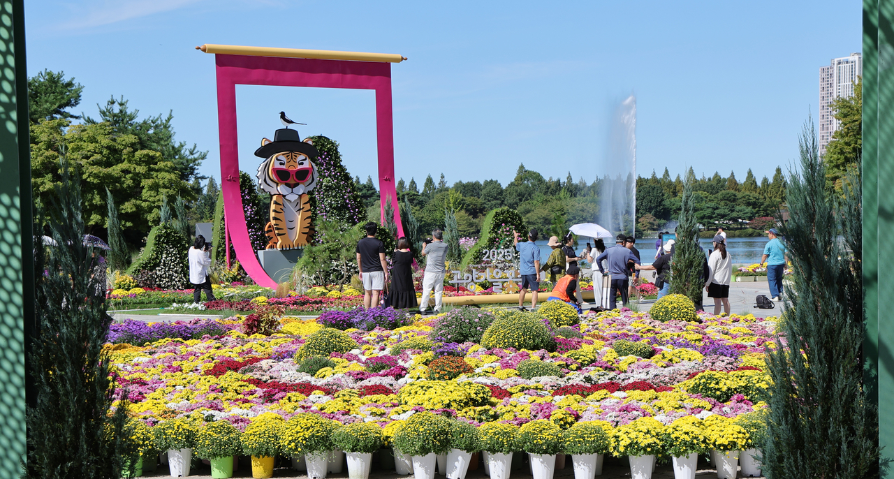 Visitors enjoy their time around autumn flowers at Ilsan Lake Park in Goyang, Gyeonggi Province, where the Goyang Autumn Flower Festival has been underway since Friday and runs through Oct. 30. (Yonhap)