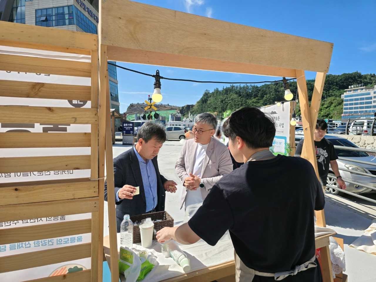 울릉하루장을 찾은 남한권 울릉군수(왼쪽)가 음식을 시식하고 있다.[울릉군 제공]