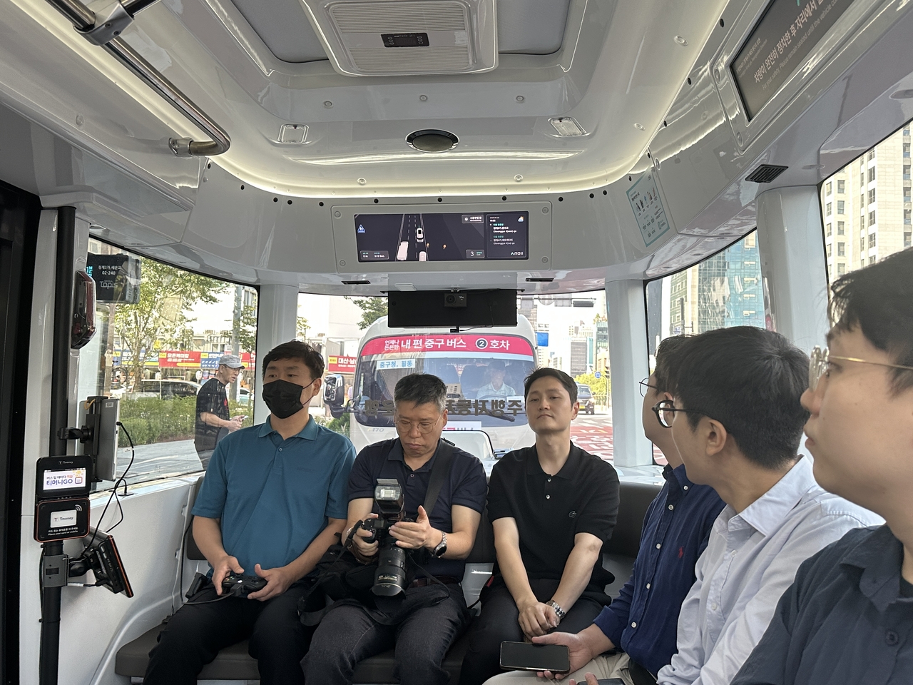 Passengers and a safety officer (left) ride on Seoul's self-driving bus along Cheonggyecheon in Jongno-gu, central Seoul, Tuesday. (Lee Jung-joo/The Korea Herald)