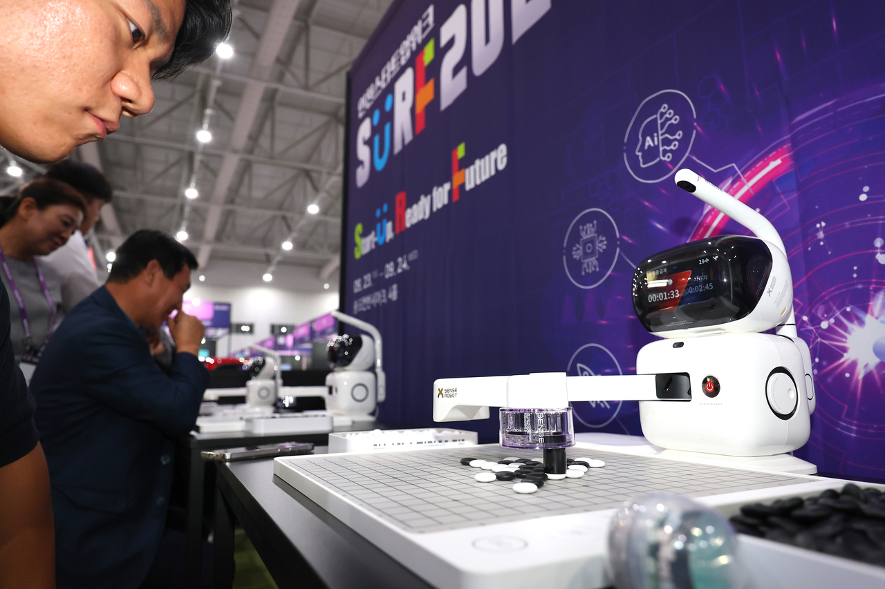A participant at SURF 2025 Incheon waits as an AI robot places its stone during an omok match on Tuesday. (Yonhap)