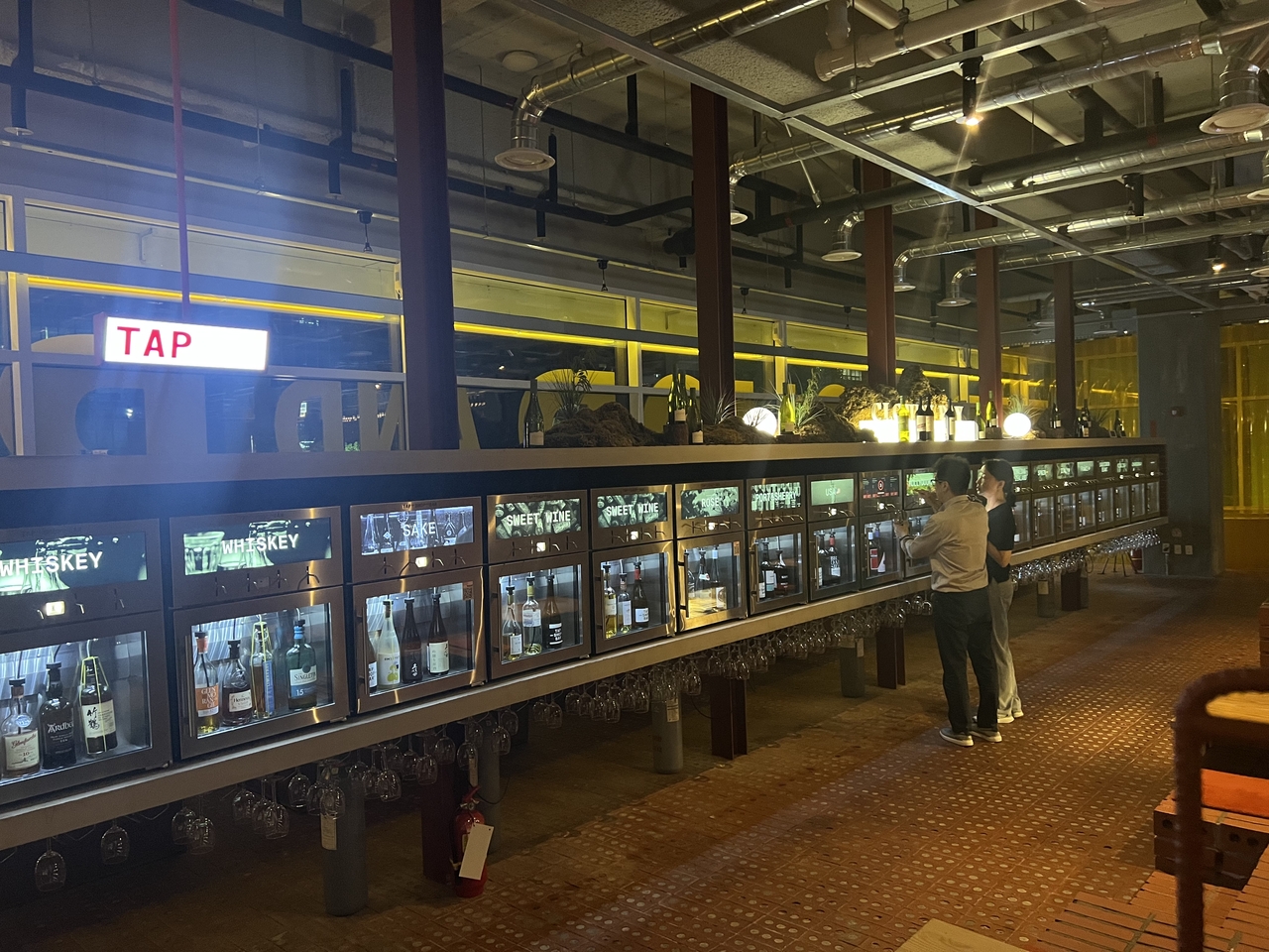A visitor pours a glass of wine from a tap at Tap and Shop and Bar on Dosandae-ro in Seoul on Sunday. (Kim Jae-heun/The Korea Herald)