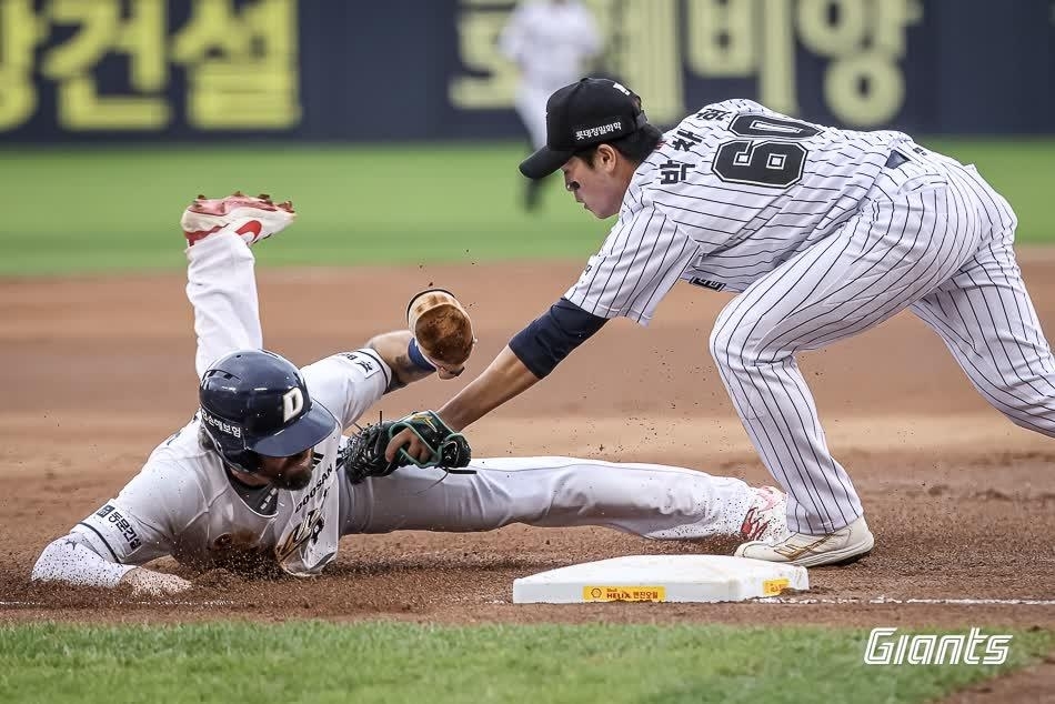 Lotte Giants third baseman Park Chan-hyung (right) tries to tag Jake Cave of the Doosan Bears during the clubs' Korea Baseball Organization regular-season game at Jamsil Baseball Stadium in Seoul on Sunday. (Yonhap)