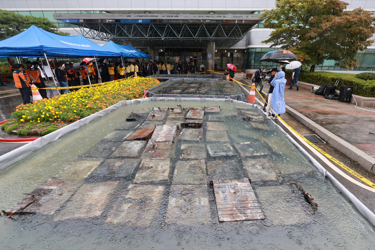 Burnt lithium-ion batteries are submerged in water tubs at the site of the fire at the National Information Resources Service in  Daejeon on Sunday. (Yonhap)