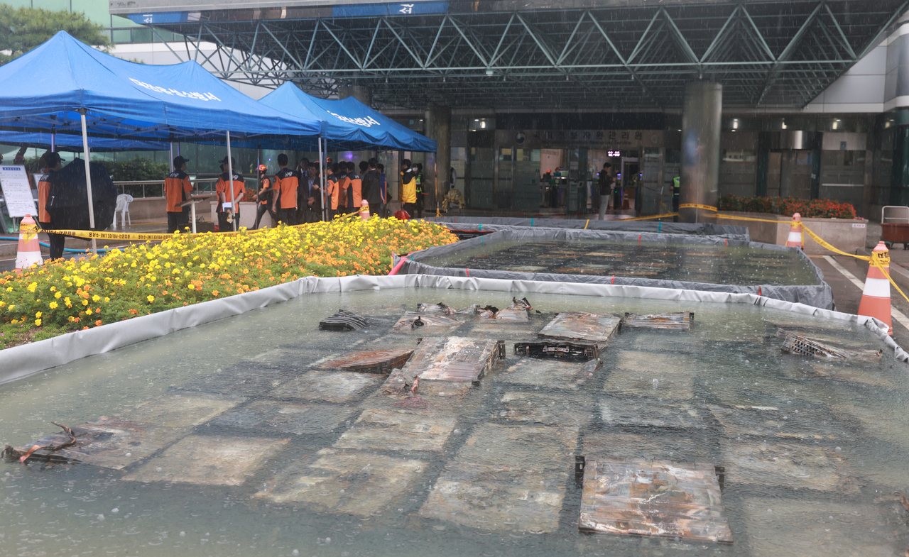 Burnt lithium-ion batteries are submerged in water tubs at the site of the fire at the National Information Resources Service in Daejeon on Sunday. (Yonhap)
