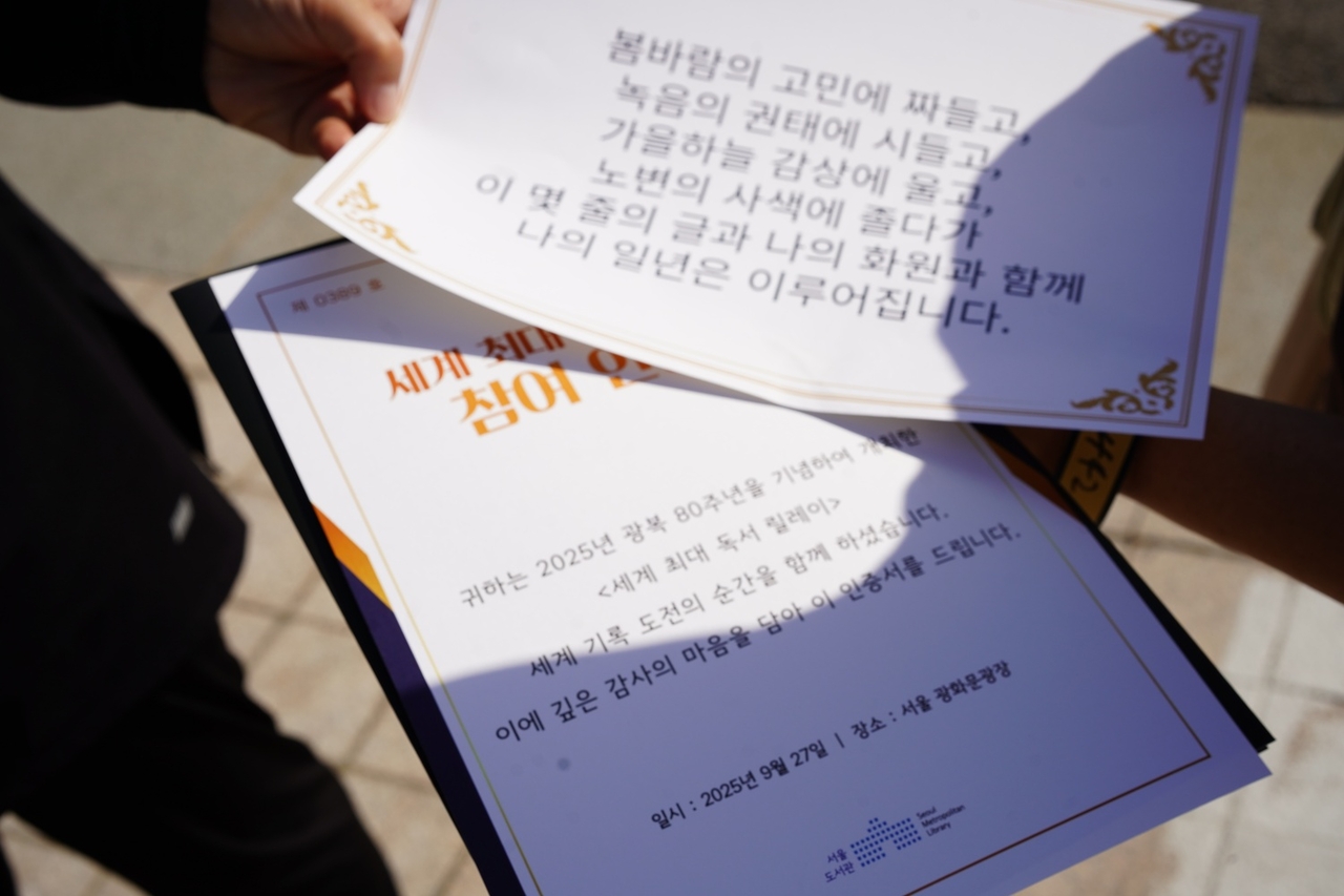 A participant shows her certificate and a paper with a line from the poem she read aloud at the event venue in Jongno-gu, central Seoul, Saturday. (Lee Si-jin/The Korea Herald)