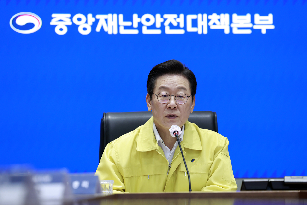 President Lee Jae Myung checks reports during an emergency meeting to discuss the response to a fire at the National Information Resources Service held at the central disaster response headquarters in central Seoul on Sunday. (Yonhap)