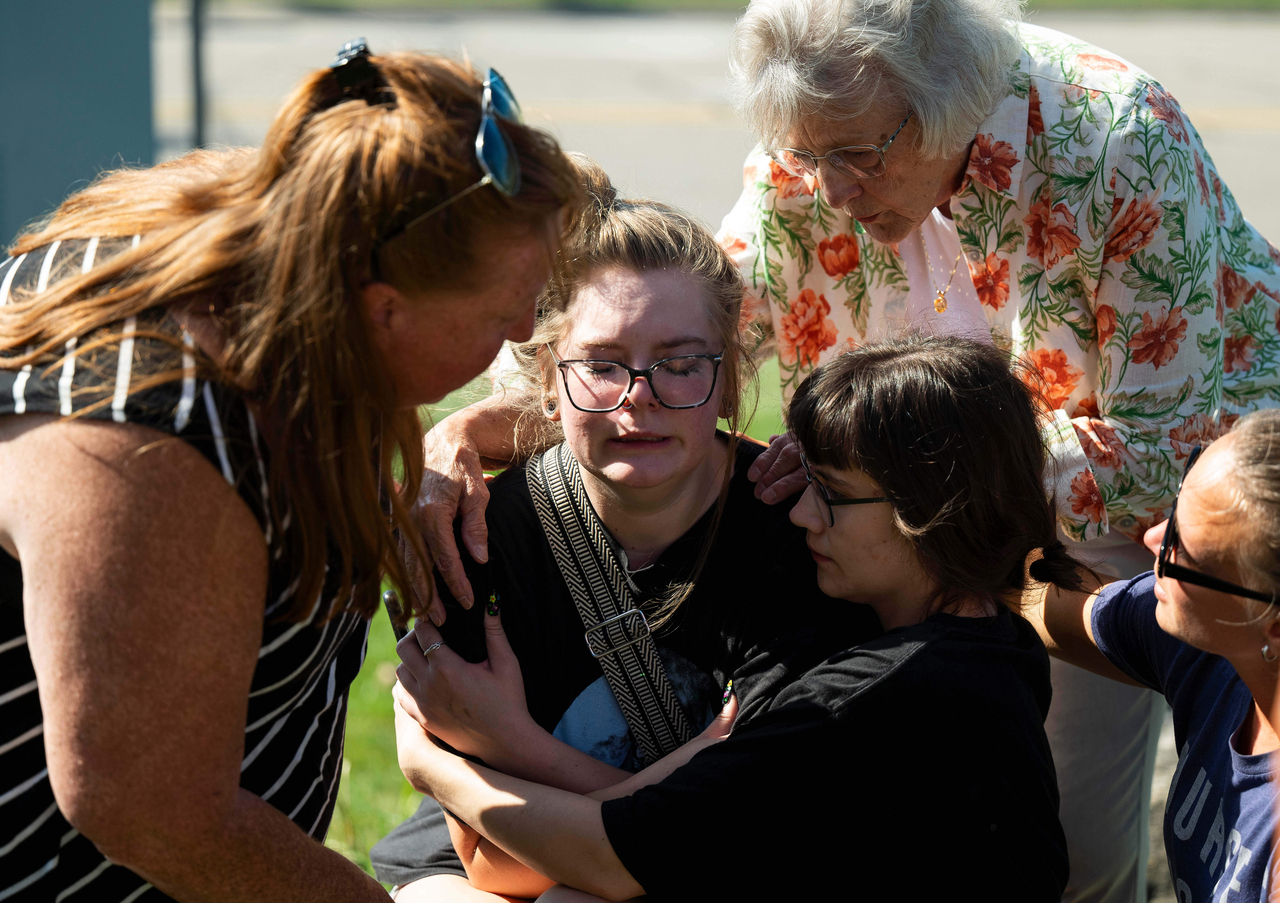 Joanne Green of Fenton, 75, top right, and McKenna Harrington of Davison, 25, second from right, comfort Katelyn Kruse of Fenton, 26, center, after Kruse was present at the scene of a shooting and structure fire at The Church of Jesus Christ of Latter-day Saints on McCandlish Road in Grand Blanc, Mich., Sunday. (AP-Yonhap)